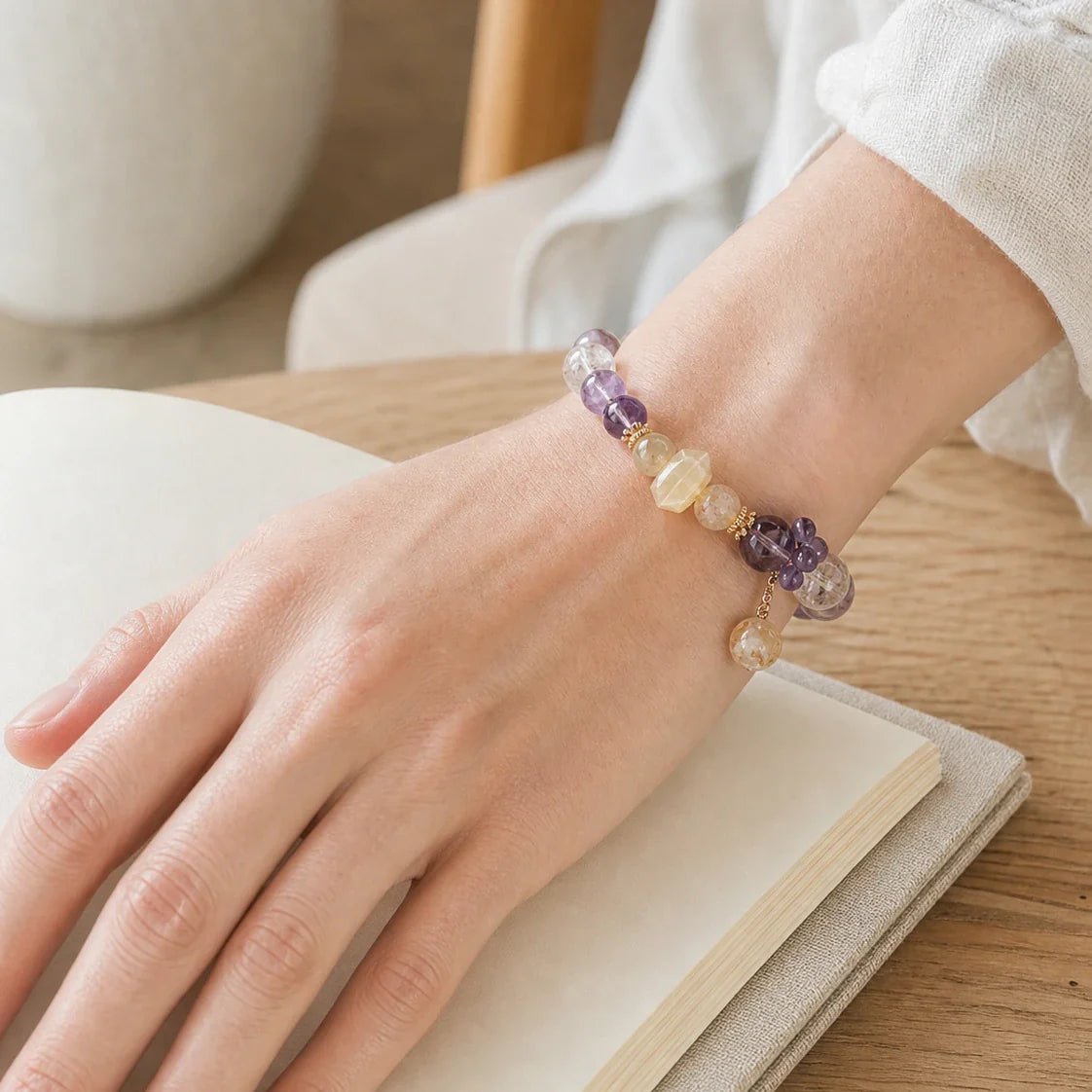 Natural amethyst and rutilated quartz bracelet worn over an open linen book