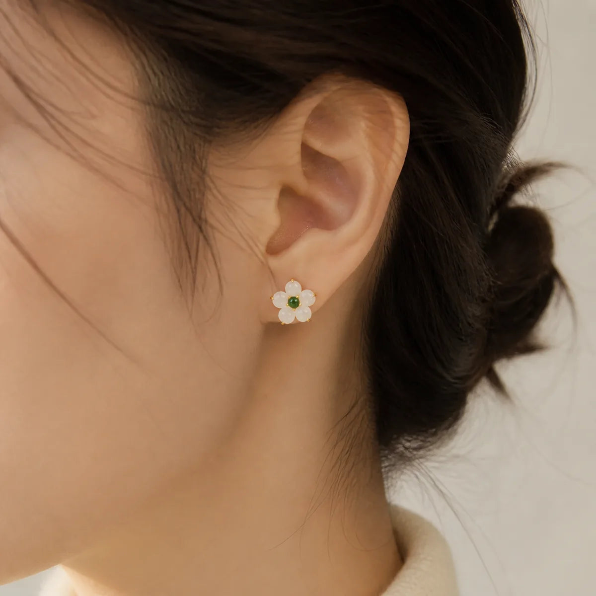 White jade flower stud earrings worn by a woman