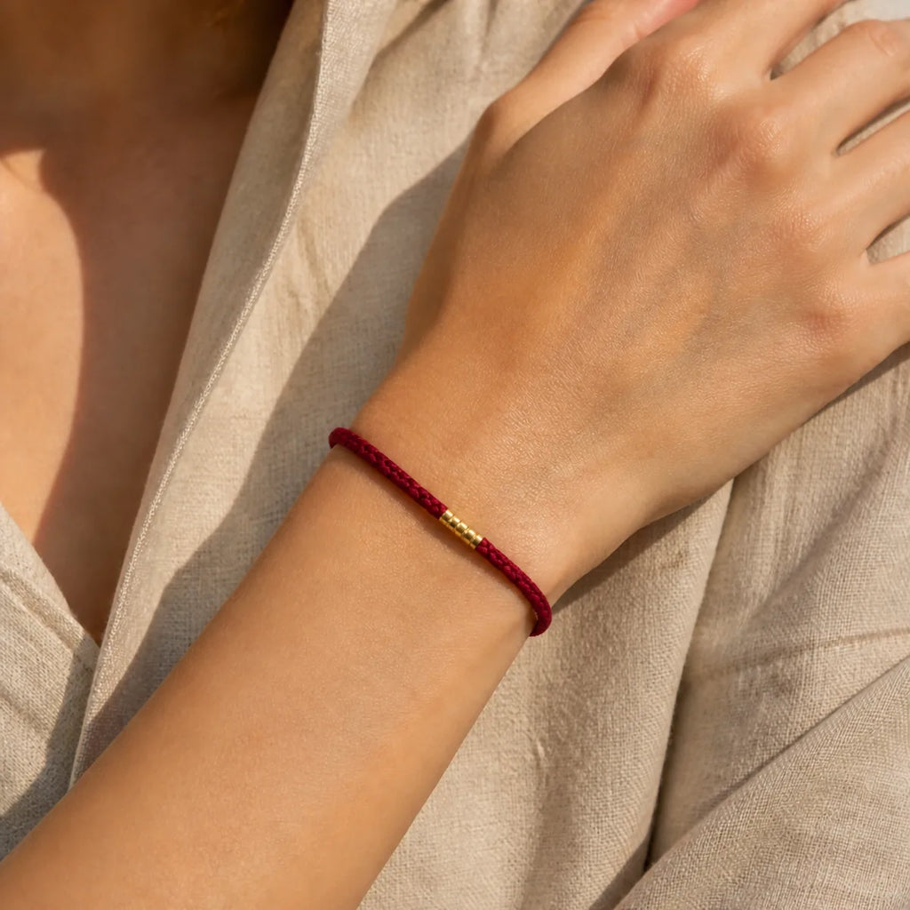 Lucky golden bead red string bracelet worn on a woman's wrist
